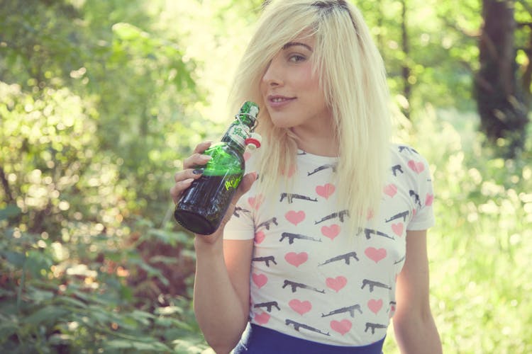 A Blonde-Haired Woman Holding A Bottle Of Beer