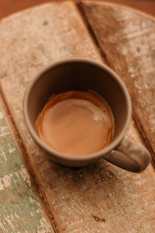 Free Warm close-up of a coffee cup on a vintage wooden table, evoking a cozy morning ambiance. Stock Photo