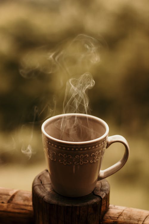 Free Steaming Mug of Coffee on Wooden Coaster  Stock Photo