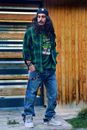 Woman in Purple and Black Plaid Long Sleeve Shirt and Blue Denim Jeans Standing Beside Brown