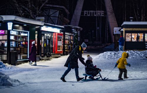 Free A family enjoys a sleigh ride on a snowy winter street at night, capturing quality time. Stock Photo