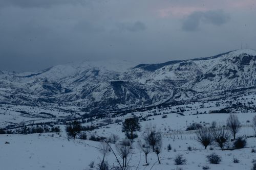 Free Captivating view of snow-covered mountains in a serene winter landscape during dusk, with moody skies. Stock Photo