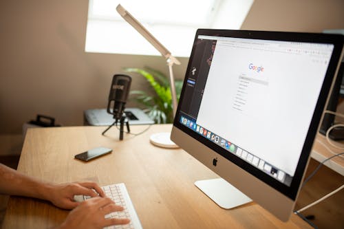 Free A Person Browsing Google on iMac Stock Photo