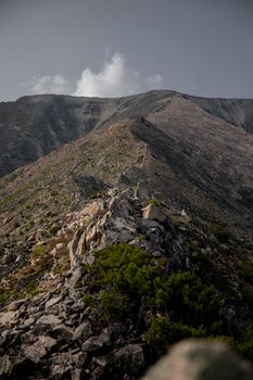 Explore the stunning rocky mountain landscape with lush greenery and a cloudy sky.