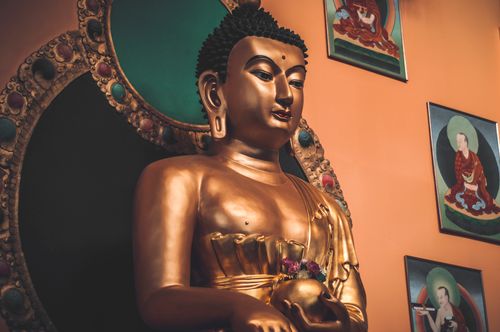Free A golden Buddha statue surrounded by artwork, symbolizing peace and spirituality. Stock Photo