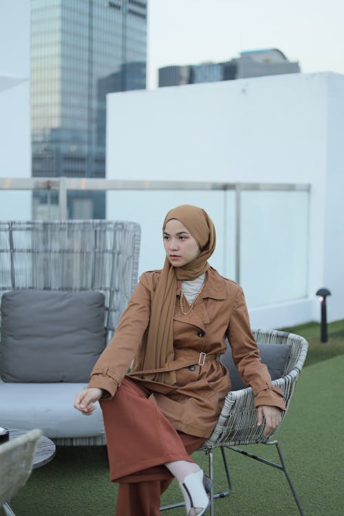 Free Hijabi Woman Sitting on Chair in Roof Garden Stock Photo