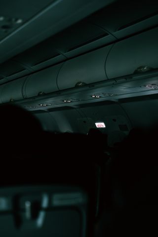 A dark, vertical shot of an airplane cabin showing an illuminated exit sign.