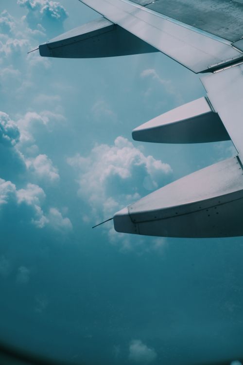 Free View from an airplane window showing the wing and cloudy sky, capturing the essence of air travel. Stock Photo