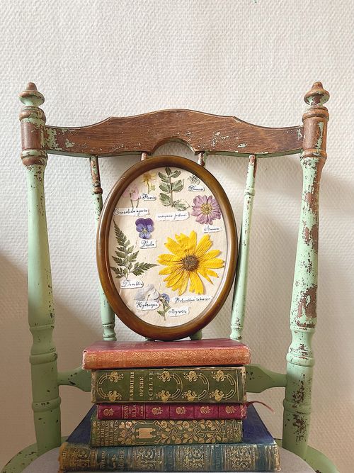 Free Charming floral art in a wooden frame on an antique chair. Aesthetic setup with stacked vintage books. Stock Photo