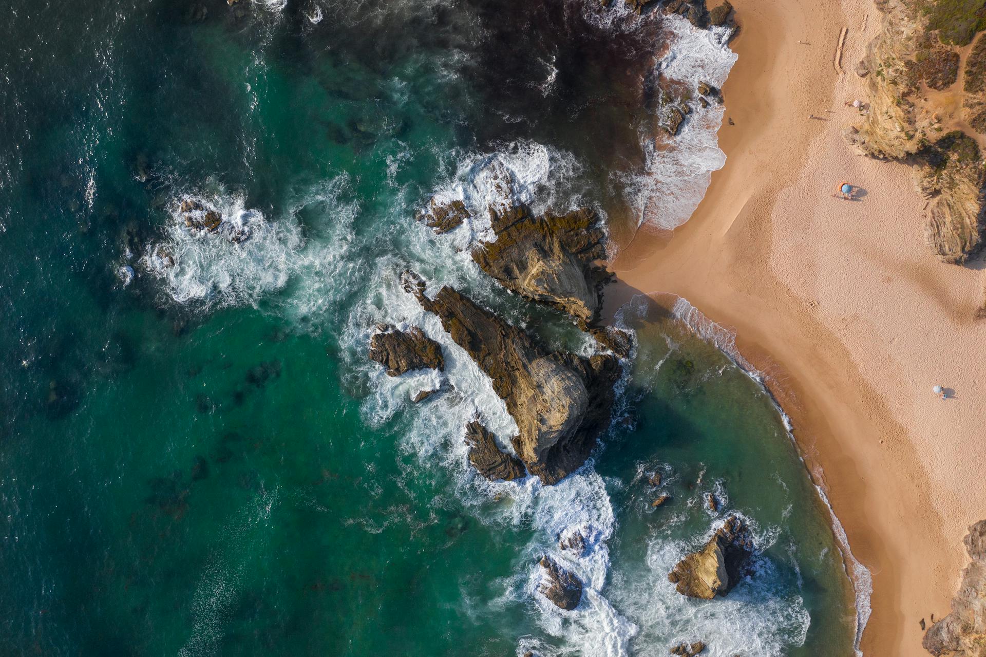 Breathtaking aerial view of rocky coastline and sandy beach in Sines, Portugal.