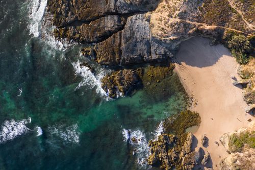 Free Stunning aerial view of a rocky beach with turquoise waters at Vila Nova de Milfontes, Portugal. Stock Photo