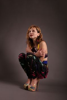 Fashionable woman in colorful attire posing expressively in a studio setting.