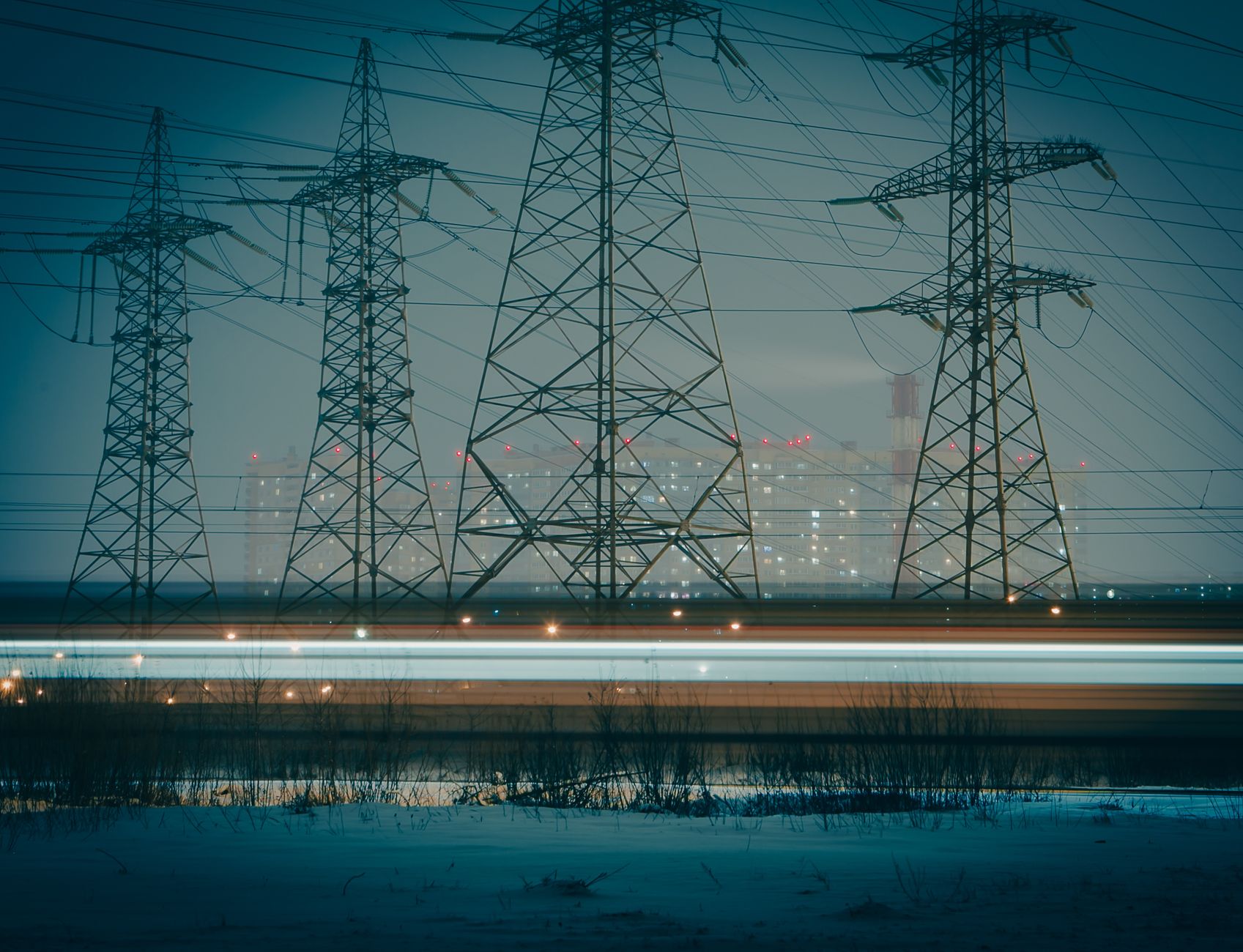 Transmission towers over a city skyline underline the electricity-demand narrative being used to market nuclear capacity to AI-era investors.