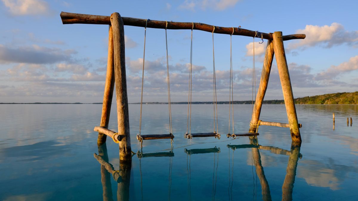 Una imagen tranquila de columpios de madera sobre las aguas turquesas de la Laguna de Bacalar, México