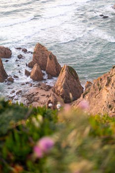 Breathtaking view of rock formations and ocean waves at Praia da Ursa, Portugal.