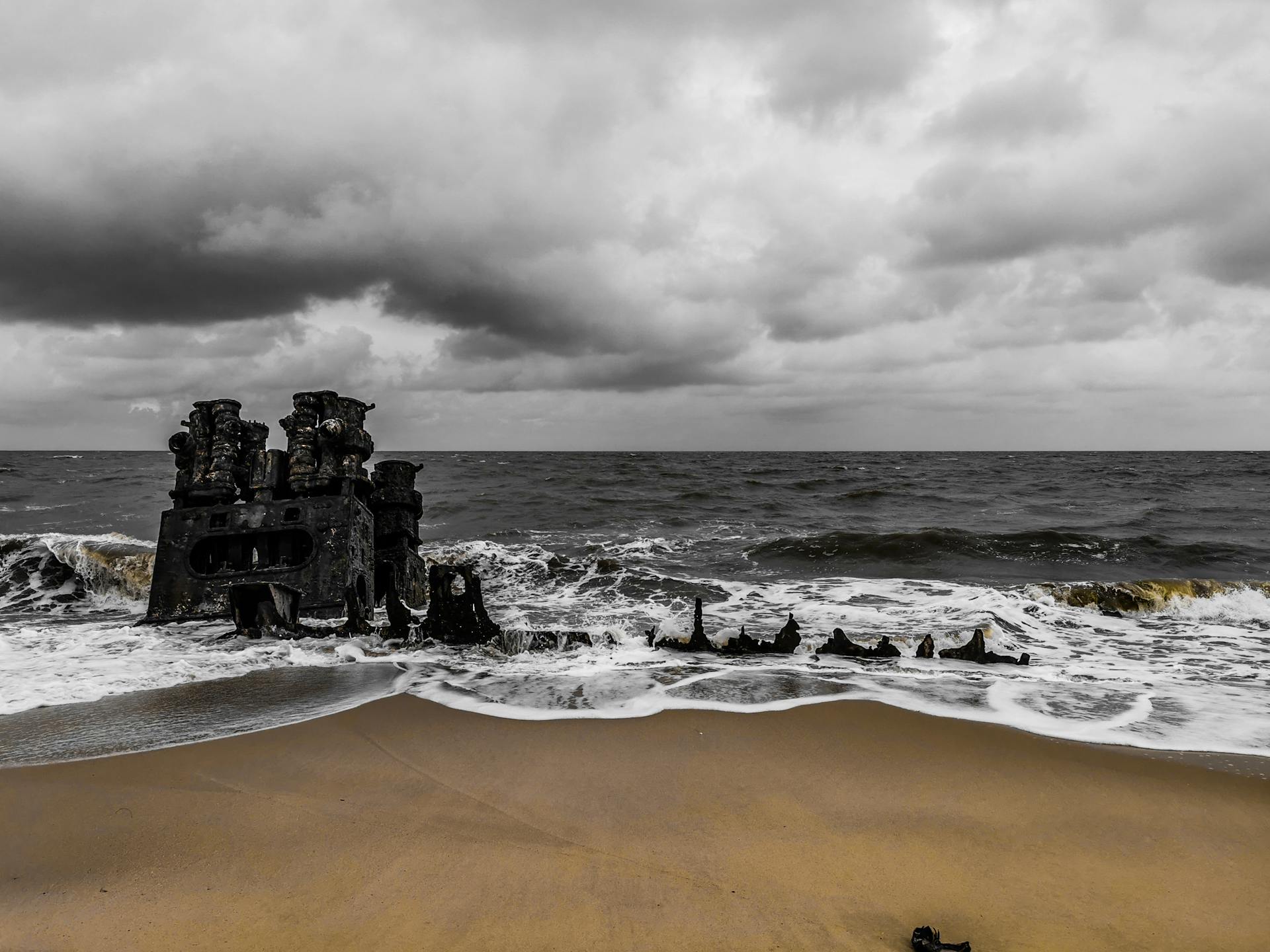 Dramatic view of a shipwreck on Beira beach with stormy skies and crashing waves in Mozambique.