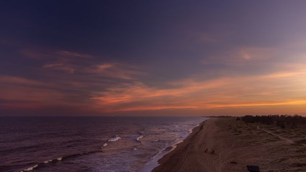 Beautiful sunset over a serene Brazilian beach with calm waves and a glowing sky.