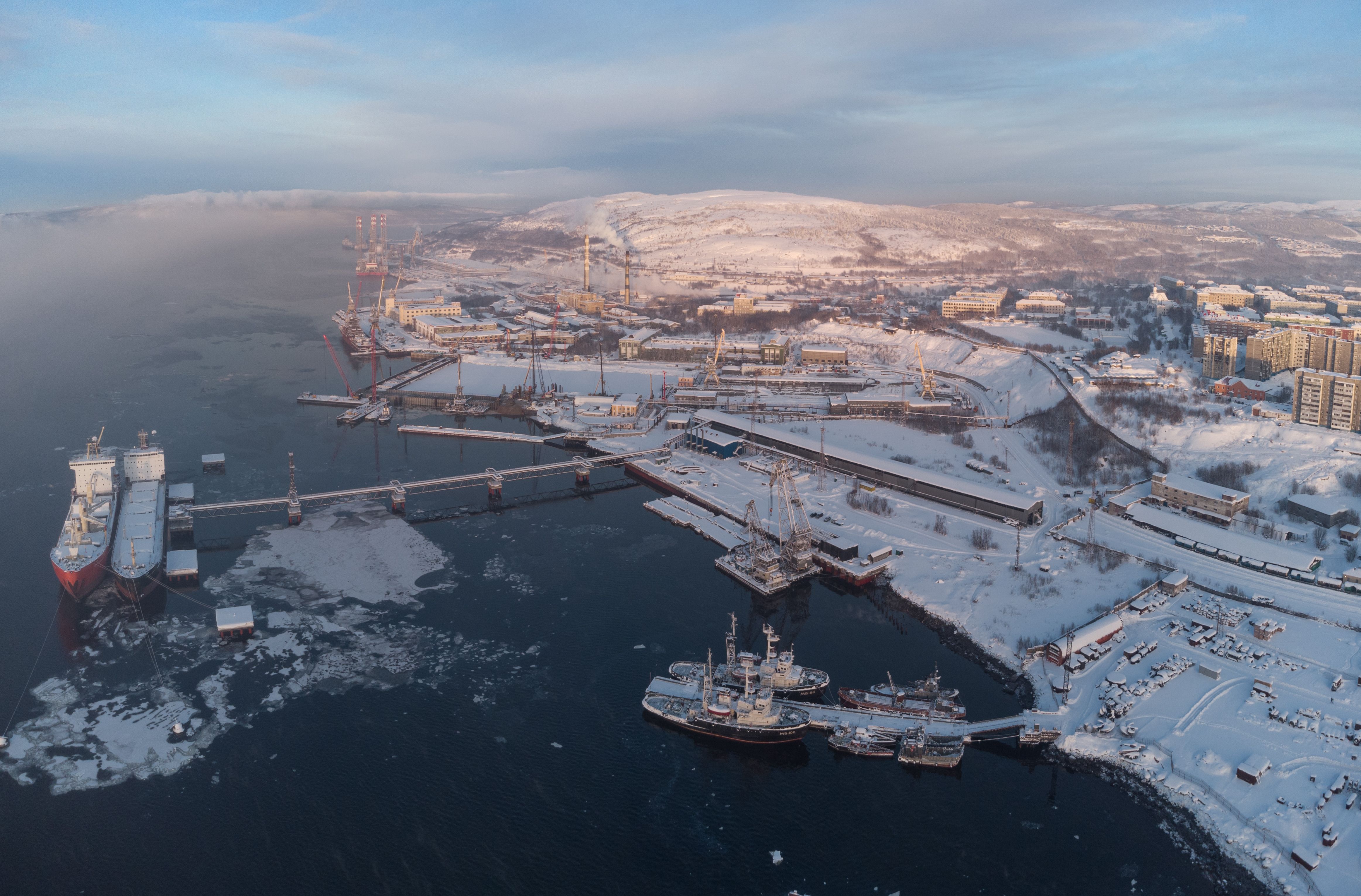 Snow-covered Murmansk harbor with cargo ships in winter, showcasing a bustling maritime scene. (Photo by Dmitry Gornaev on Pexels)
