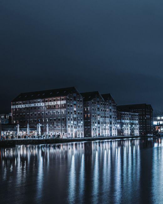 Illuminated buildings reflecting on water at Gloucester Docks, England.