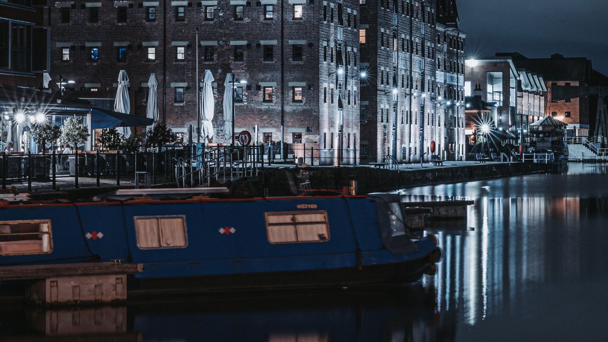 Historic brick warehouses reflected in the water of Gloucester Docks at night