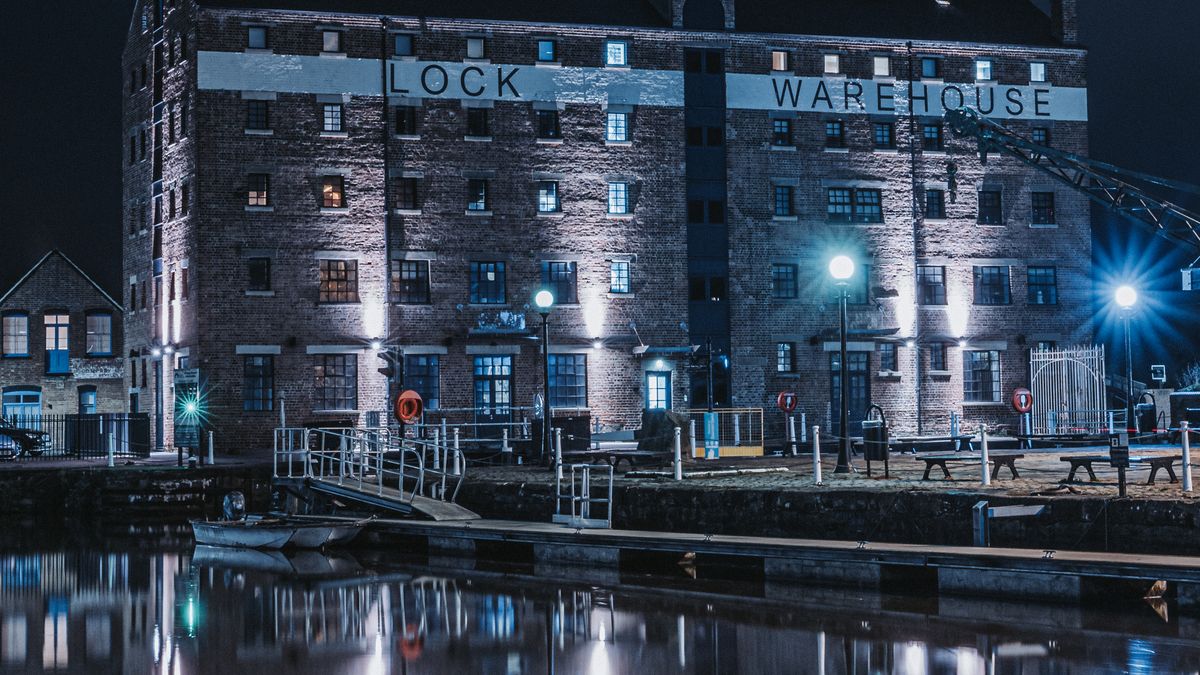 The Lock Warehouse at Gloucester Docks lit up at night and reflected in the dock basin