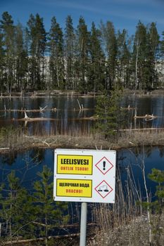 A Warning Sign Near a River Near Green Trees