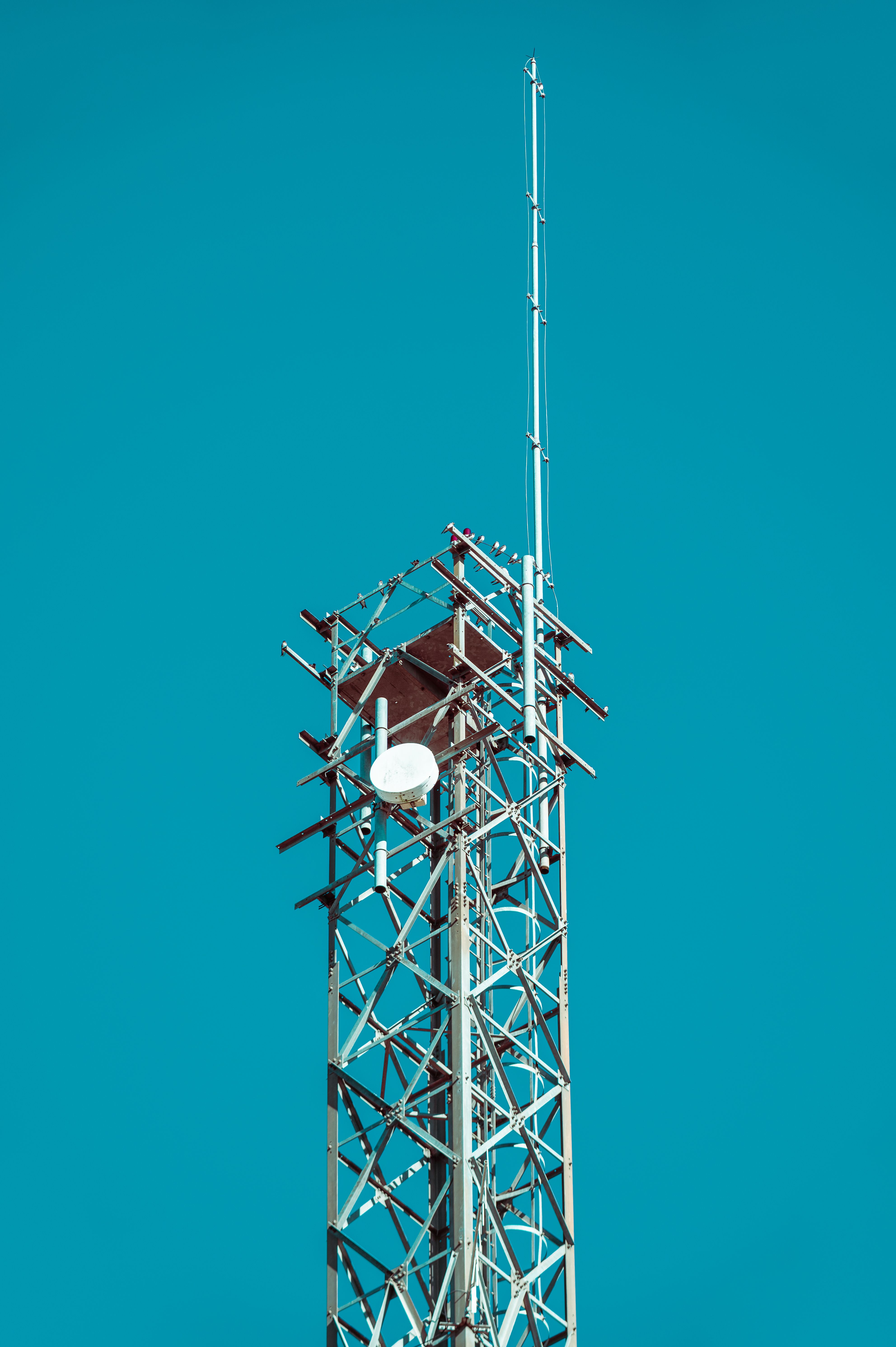 A metal communication tower with antennas set against a vivid blue sky.