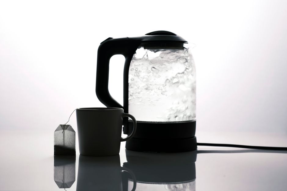 Silhouette of an electric kettle and a tea cup with a tea bag on a white background.