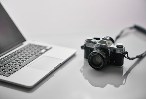 Free A vintage Canon camera and modern laptop are placed stylishly on a reflective desk. Stock Photo