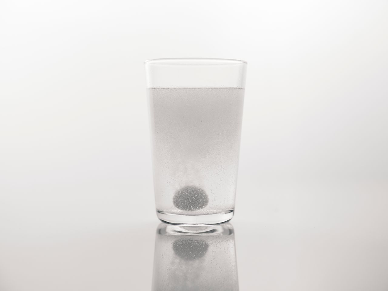 Effervescent tablet dissolving with bubbles in a clear glass of water