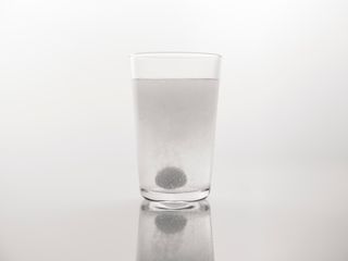 Effervescent tablet dissolving with bubbles in a clear glass of water