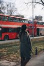 Woman in Black Coat Standing Near Red Bus