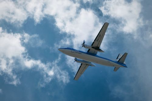 Free Airplane flying above with a backdrop of clouds against a bright blue sky in England. Stock Photo