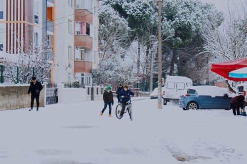 Free Kids enjoy a snowy day in Gönen, Türkiye, riding bikes and playing outdoors. Stock Photo