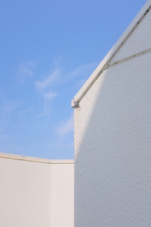 Free White textured walls against a bright blue sky, showcasing minimalist architecture and simplicity. Stock Photo