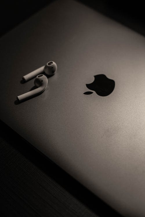 Close-Up Shot of White Earbuds on a Silver Macbook