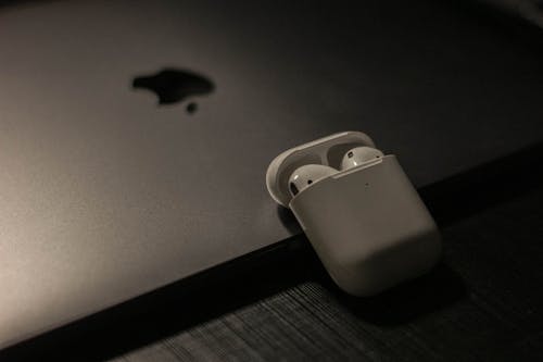 Close-Up Shot of Wireless Earbuds beside a Macbook