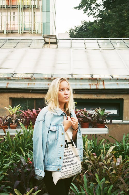 Woman Wearing White Shirt and Denim Jacket Standing Near House