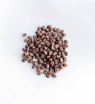 Close-up of aromatic roasted coffee beans on a white surface, viewed from above.