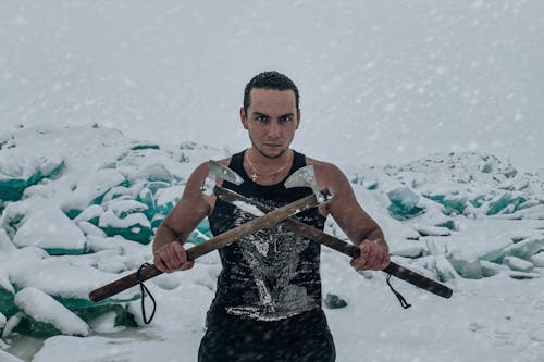 Man in Black Tank Top Holding Brown Wooden Stick