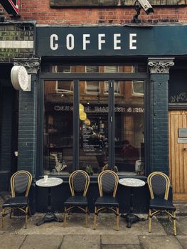Charming coffee shop facade in Manchester with stylish chairs and tables outside.