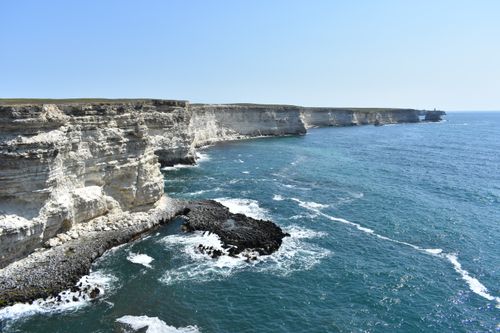 Free Stunning rocky coastal cliffs meeting the ocean under a clear sky, showcasing natural beauty and rugged scenery. Stock Photo