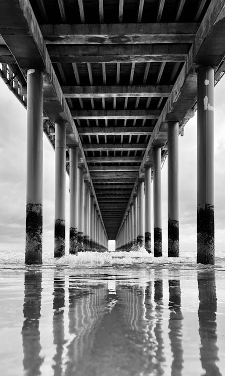 Free Grayscale Photo of Rushing Waves Under a Bridge  Stock Photo