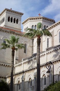 White stone building with palm trees under a vibrant blue sky.