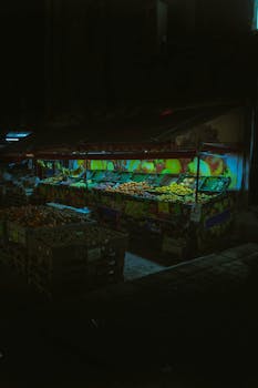 A vibrant fruit market stall illuminated at night in Tirana, Albania.