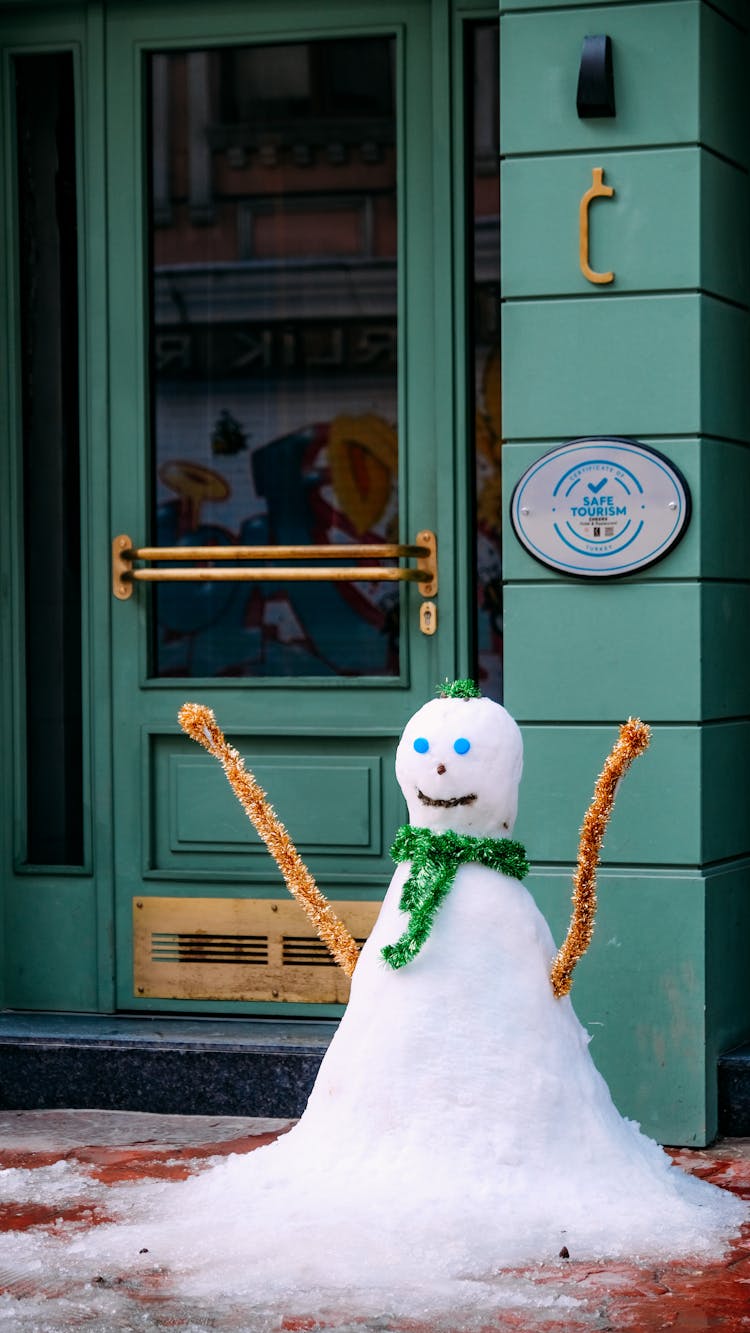 Snowman In Front Of A Shop With Green Door