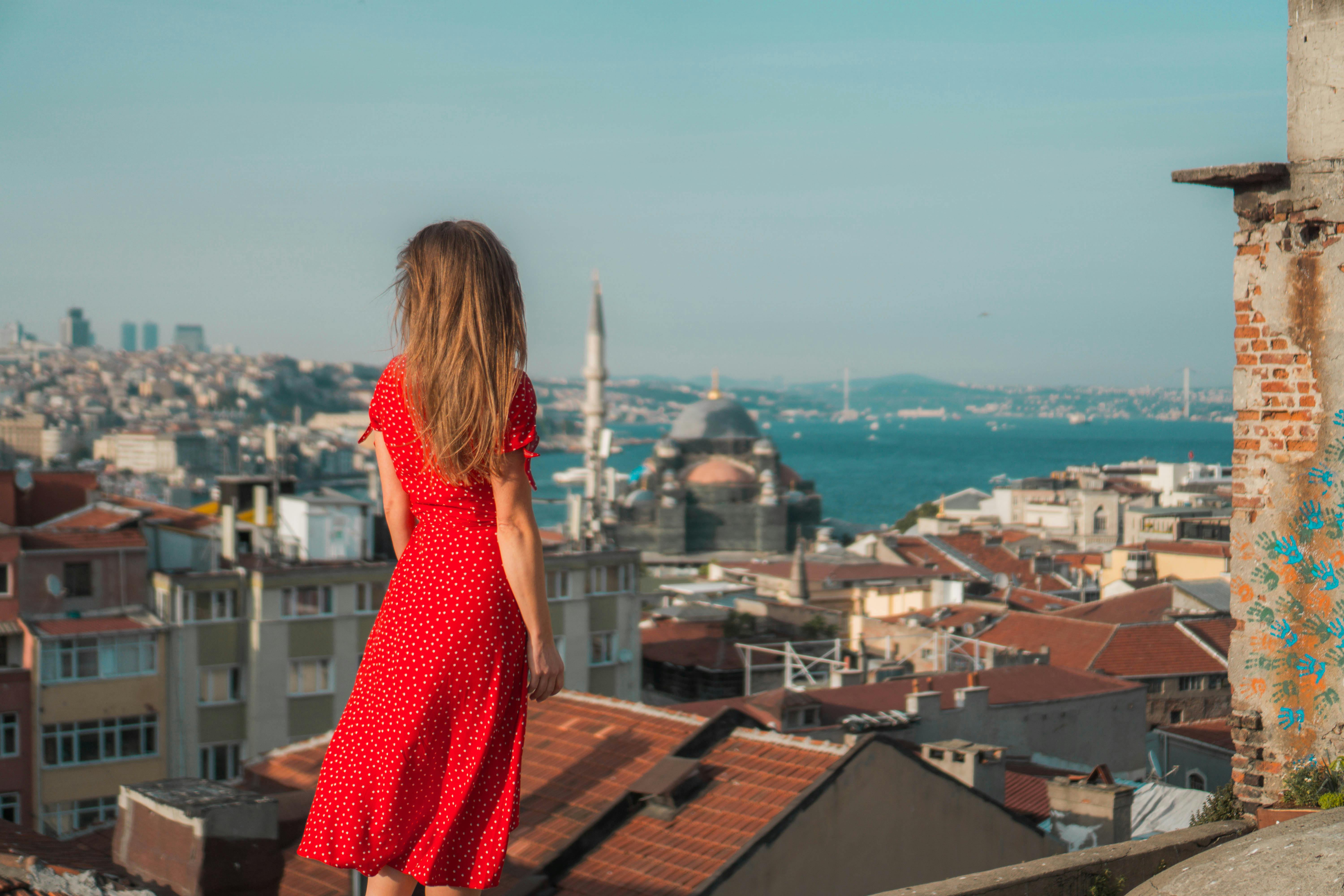 Woman in red polka dot dress overlooking the scenic Istanbul skyline with Bosphorus and domes.