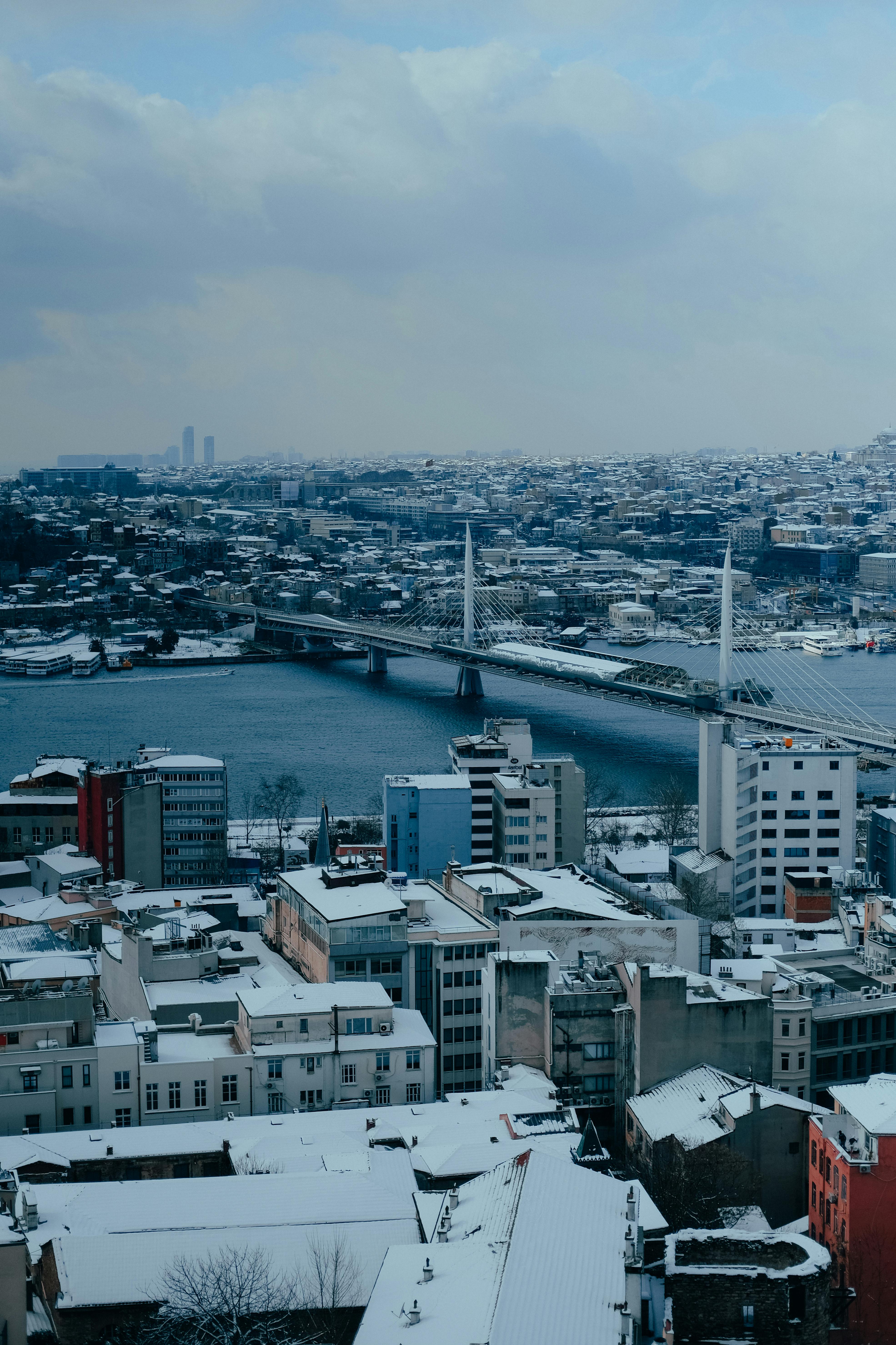 Aerial view of a snowy cityscape featuring a prominent bridge over a river.