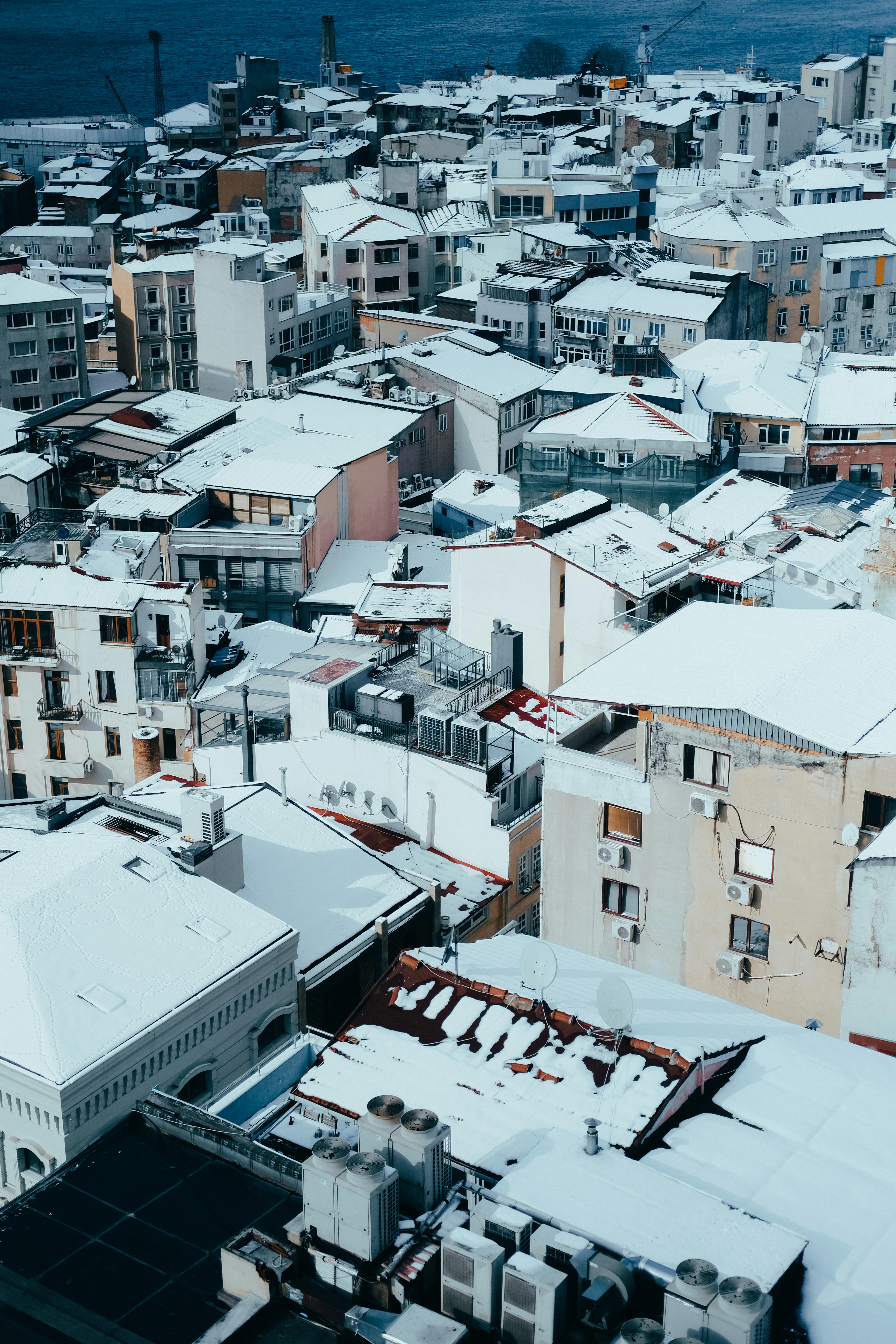 Aerial view of a snow-covered cityscape with diverse architectural styles, captured in winter.