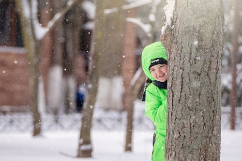 Free A Kid Hiding behind a Tree Trunk Stock Photo